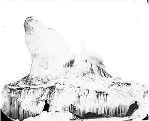 Image of Sledge, two men at base of iceberg